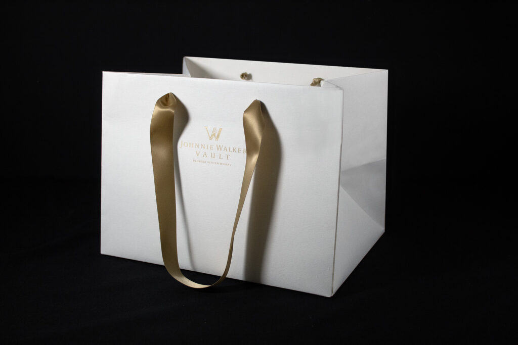 Johnnie Walker Vault Luxury paper carrier bags manufactured using Colorplan Bright White Embossed stock with gold foil branding and ribbon handles